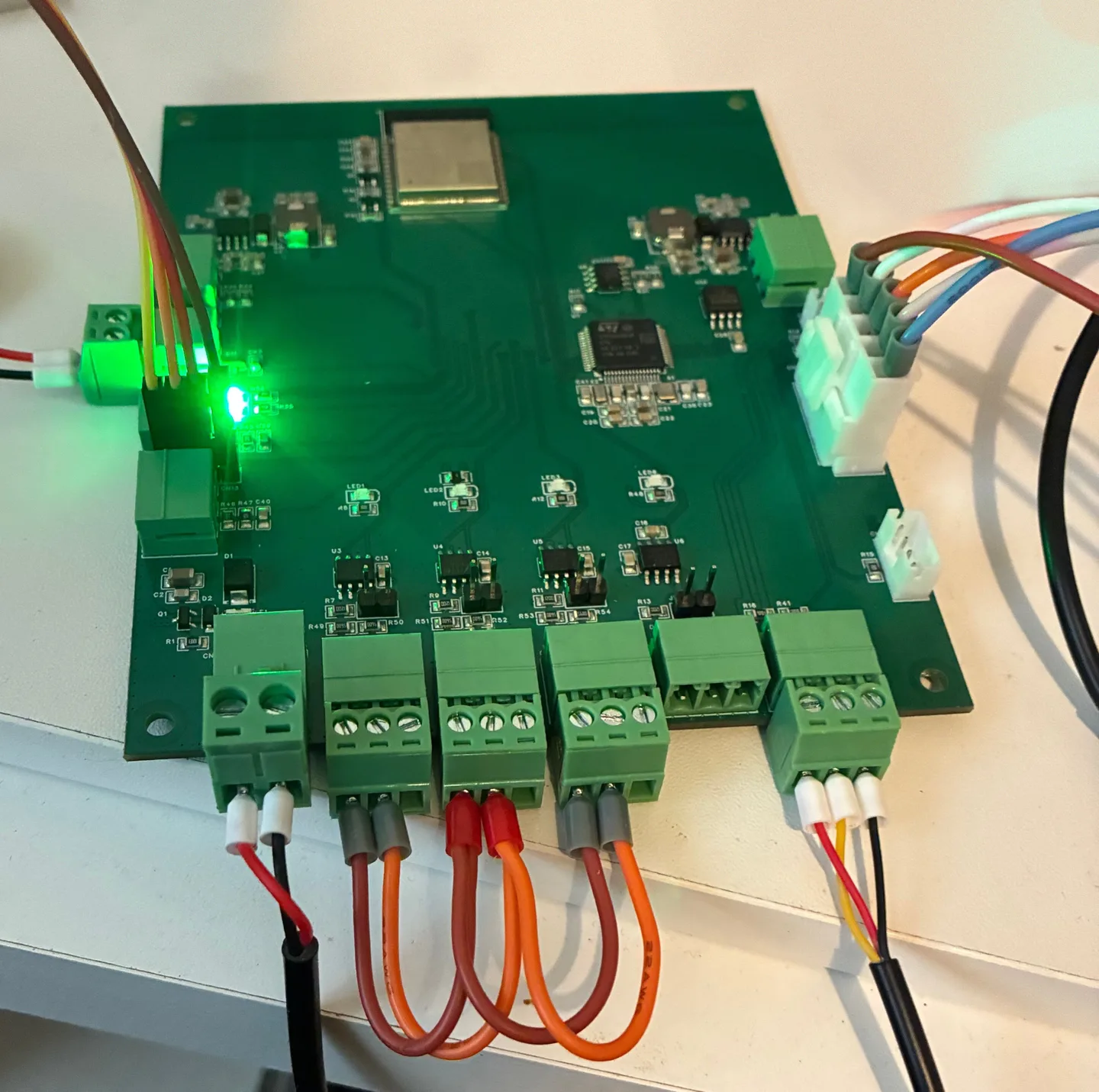 Board A on the bench, powered, with a green lamp lit, wire loops joining three of its RS-485 terminals and test cables attached